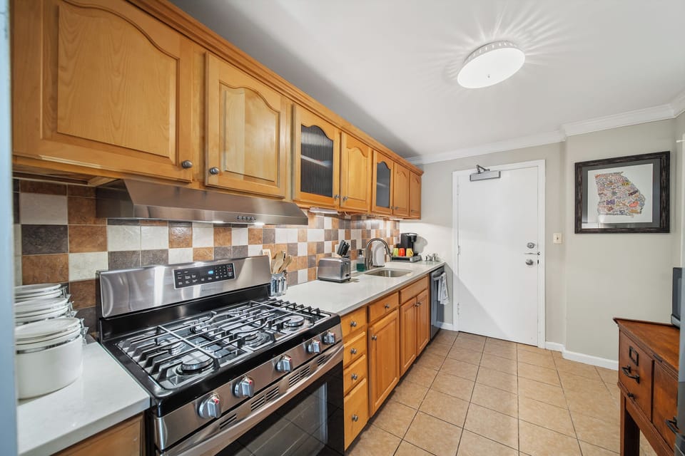 Bright kitchen workspace w/ long counter, upper cabinets & modern appliances