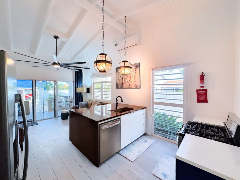 Kas di Almendra features an open concept living room and kitchen with high ceilings, a celing fan, and air conditioning- creating a bright, breezy space perfect for relaxing in comfort.