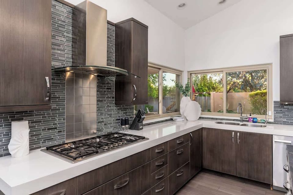 Cook up your favorite meals in this stunning modern kitchen with sleek appliances, elegant tile backsplash, and garden views that inspire culinary creativity.