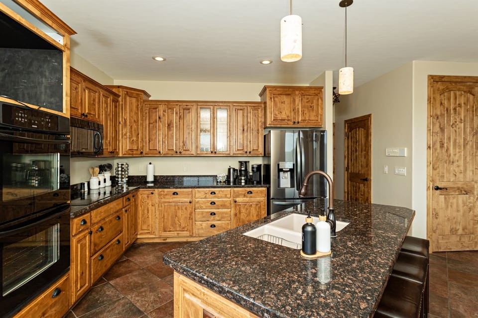 Chef's dream kitchen at The Sanctuary. Rustic knotty alder cabinets paired with sleek granite countertops. High-end appliances for gourmet cooking. Spacious island perfect for meal prep or casual dining. Create memorable meals in this Prescott retreat