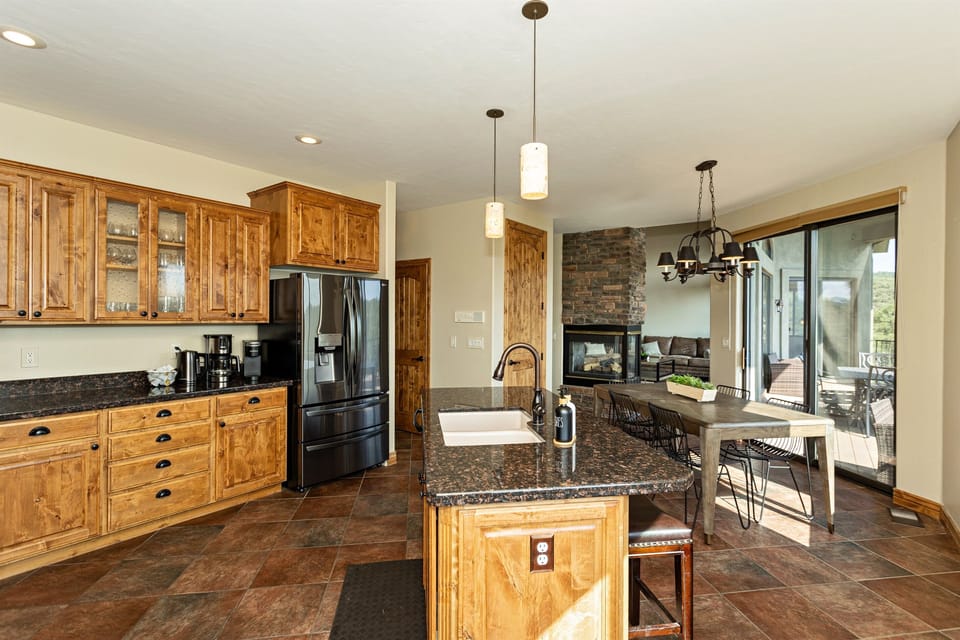 Gourmet kitchen with mountain views at The Sanctuary. Rustic charm meets modern luxury. Granite counters, stainless appliances, and cozy fireplace. Perfect for family meals or entertaining. Close to downtown Prescott, sleeps 16