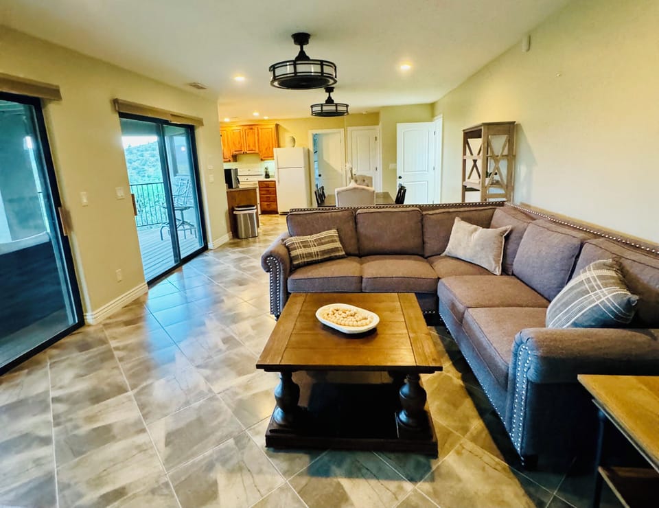 Open-concept living at The Sanctuary: Cozy sectional, stylish decor, and balcony access. Unwind after exploring Prescott's charm. Fully equipped kitchen nearby for easy entertaining. Ideal for groups seeking comfort and convenience downtown