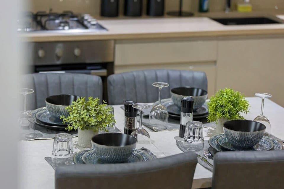 - Dining setup with stylish bowls plates and cutlery  
- Comfortable chairs surround the bright dining table  
- Perfect for gathering and enjoying meals together  