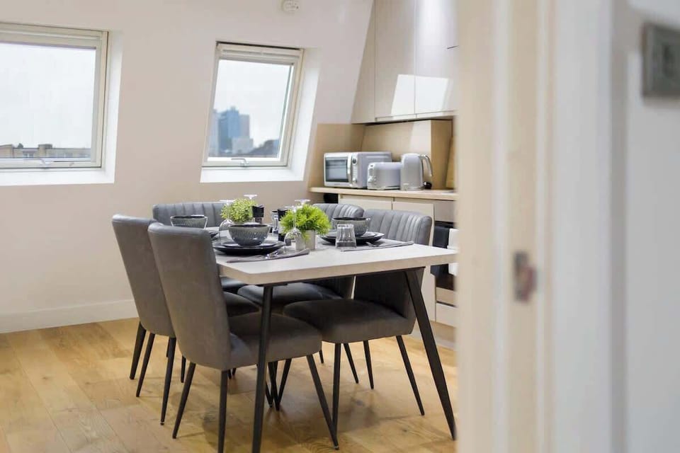 - Modern dining area set under bright skylight windows  
- Comfortable chairs and table ideal for shared meals  
- Fresh setup with city views creating memorable moments  