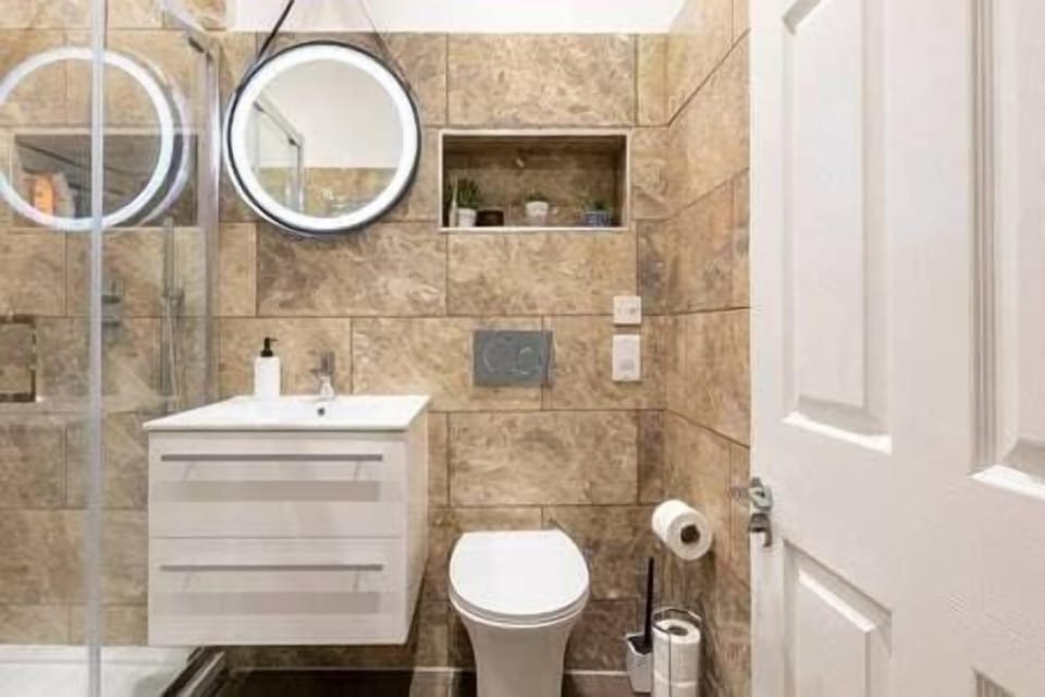 - Bathroom with walk-in shower and rainfall head  
- Floating vanity with storage and bright mirror  
- Contemporary tiled walls with built-in shelf  
