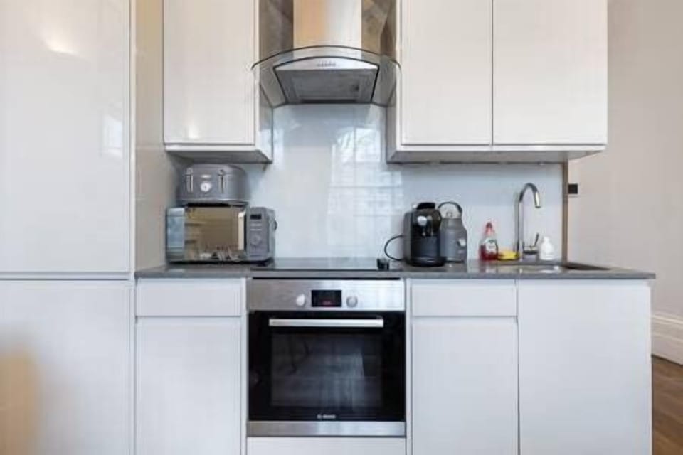 - Fully equipped kitchen with oven and appliances  
- Sleek white cabinetry and modern sink design  
- Convenient setup for easy cooking and dining 