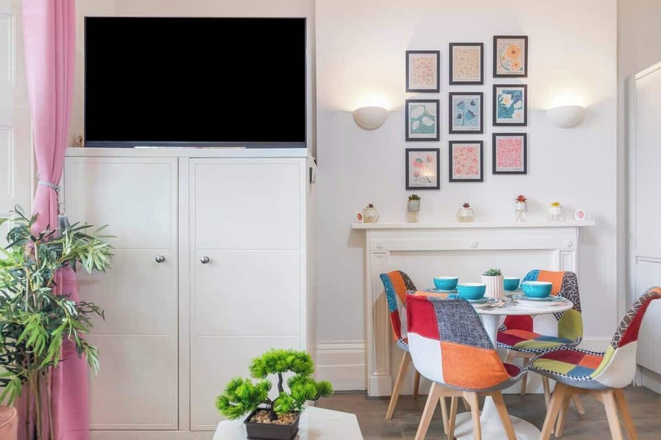 - Dining area with colorful chairs and round table  
- Wall art display creates cheerful modern style  
- TV and storage cabinet add comfort and function  
