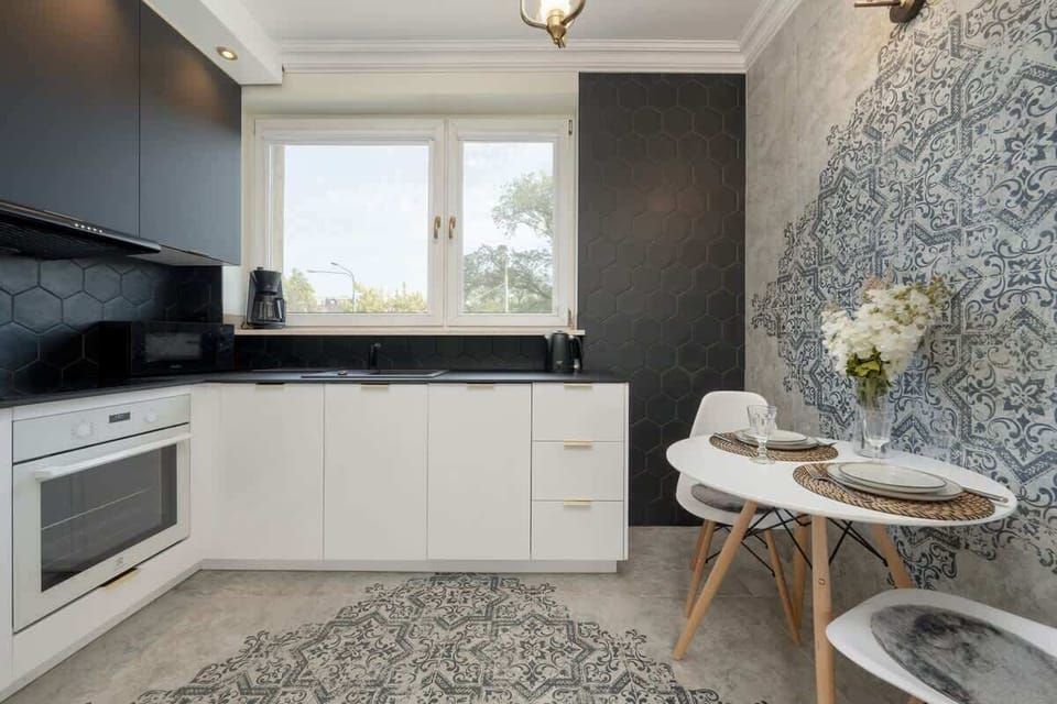 A compact, well-equipped kitchen with black countertops, under-cabinet lighting, and a clean, monochromatic palette.