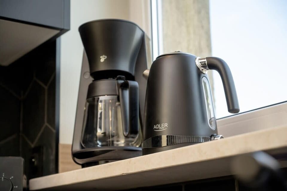 A close-up of a kitchen counter featuring a kettle and coffee maker — a compact, fully stocked setup for everyday convenience.
