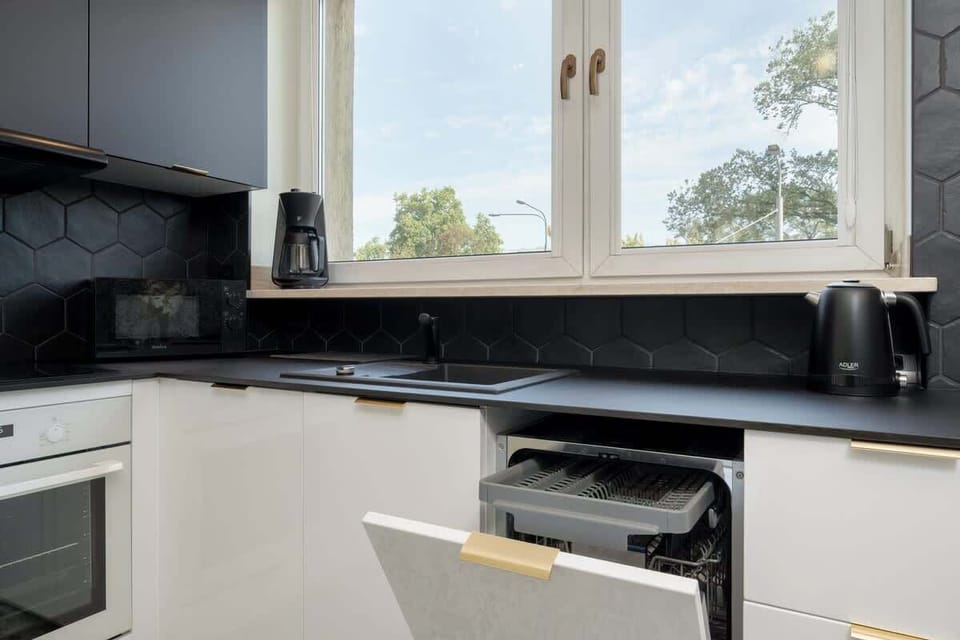 A tidy view of the cooking area with under-sink storage, oven, and a polished black granite worktop.
