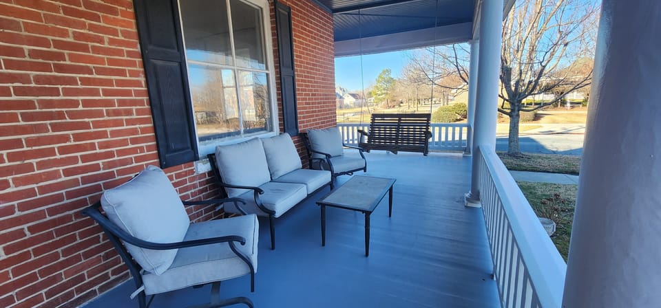 Front Porch seating with porch swing with a park side view