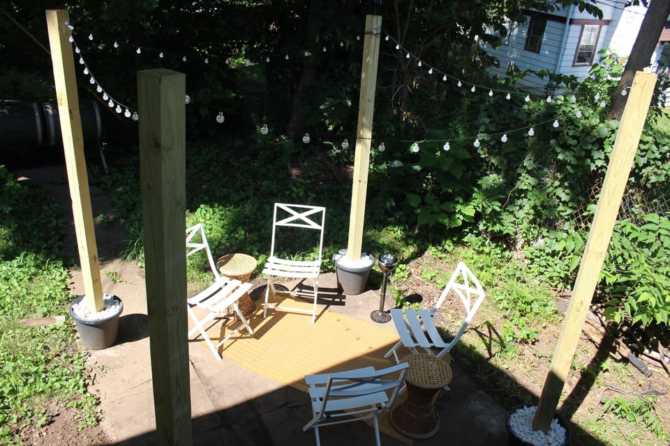 Backyard space with 4 chairs, 1 center table (not shown), solar stringed lights
