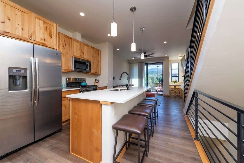 - Bright & open, this kitchen features natural wood cabinets, stainless appliances, and pendant lighting
- Long island with leather stools is perfect for breakfast, snacks, or cocktails
- Everything flows into the living space for easy entertaining