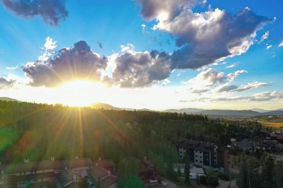 Breathtaking mountain sunset casting light over forest rooftops.