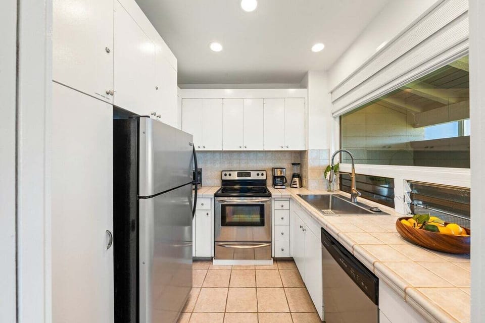 Modern, fully equipped kitchen with stainless steel appliances, white cabinetry, ample counter space, and recessed lighting for easy meal prep.