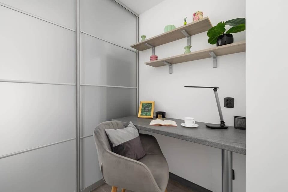 Small bedroom or study area with a desk, shelving, and a single bed, ideal for work-from-home or study.