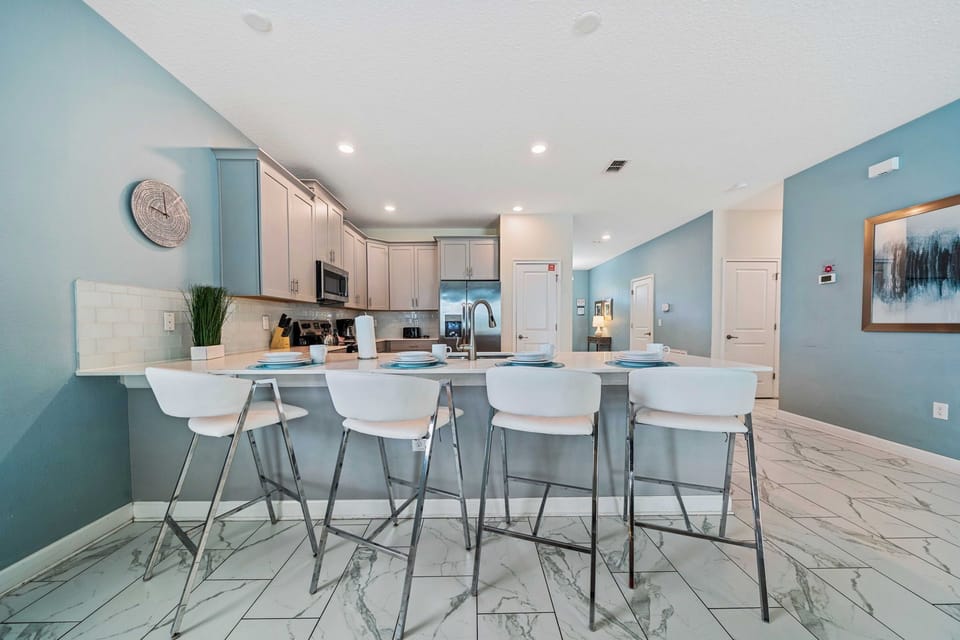 - Modern kitchen is equipped with stainless steel appliances, breakfast bar with high chairs for four - Cabinetry and marble tile flooring enhance the kitchen's elegant and contemporary design - Open layout ensures a seamless connection to dining
