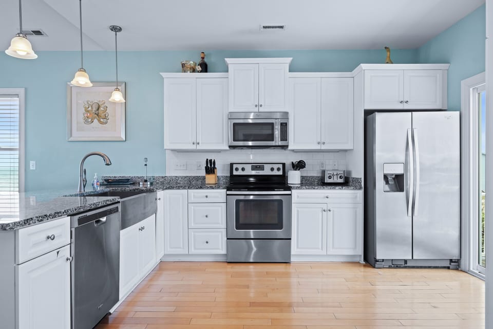 Your fully equipped kitchen features modern stainless steel appliances, granite countertops, and crisp white cabinetry—perfect for preparing meals during your stay.