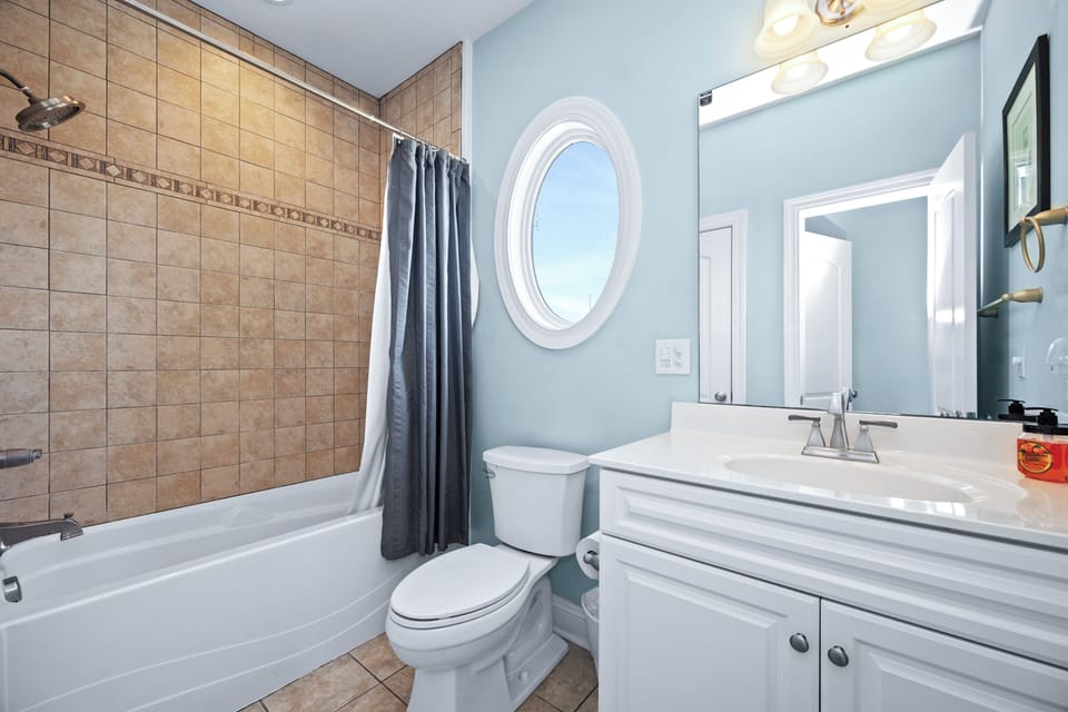 Freshen up in your bright, clean bathroom with a generous tub-shower combo, elegant oval window, and crisp white vanity—all the essentials for your comfort.