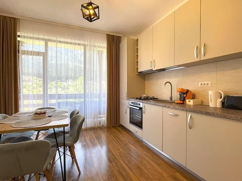 The modern open-space kitchen featuring a 2-burner stove, a dishwasher, toaster, Nespresso machine, coffee capsules, hood, water kettle, dining tables for 6 people, room-darkening shades and stunning mountain view from the balcony