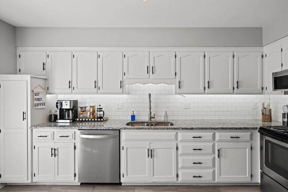 Bright, fully equipped kitchen with ample cabinetry, stainless steel appliances, and clean subway tile backsplash.