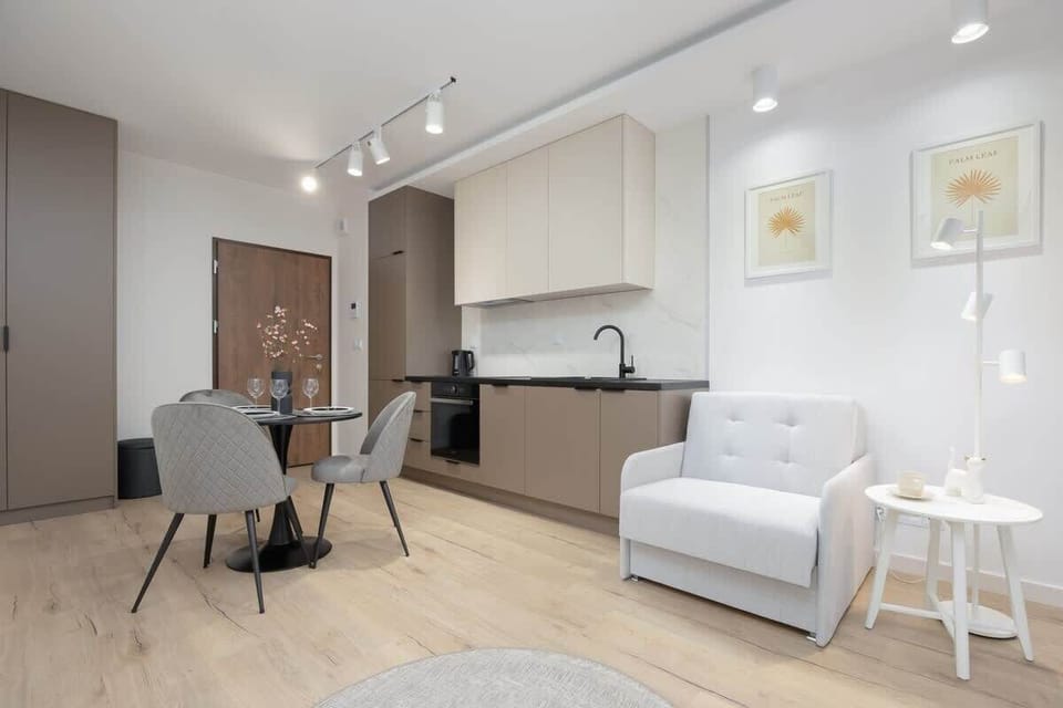 A cozy open-plan living area with a comfortable white sofa and wood accents. Natural light fills the room, creating a warm atmosphere.