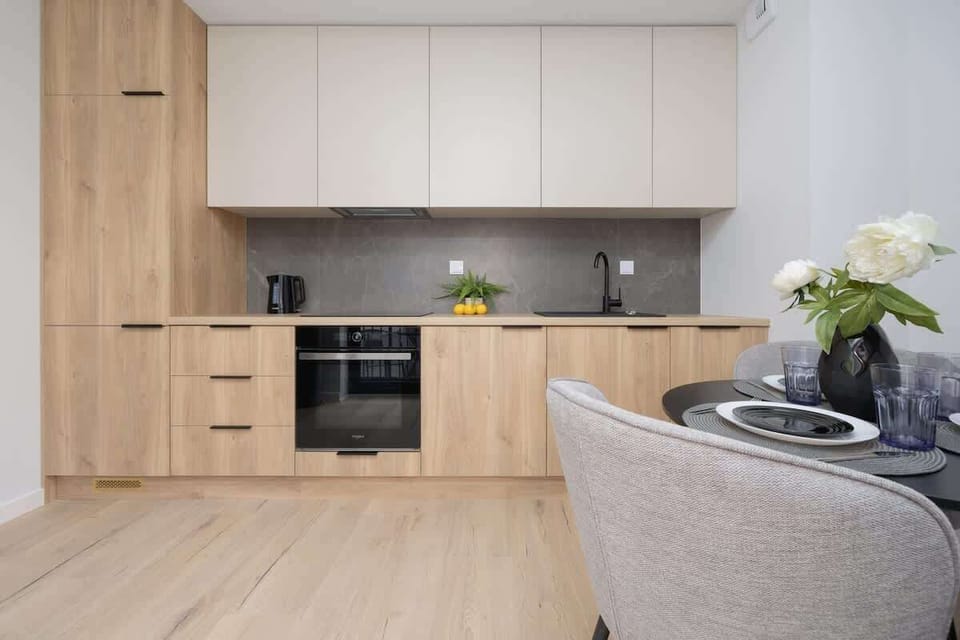A functional kitchenette with modern appliances, wooden cabinets, and a sleek black countertop—ideal for everyday cooking.