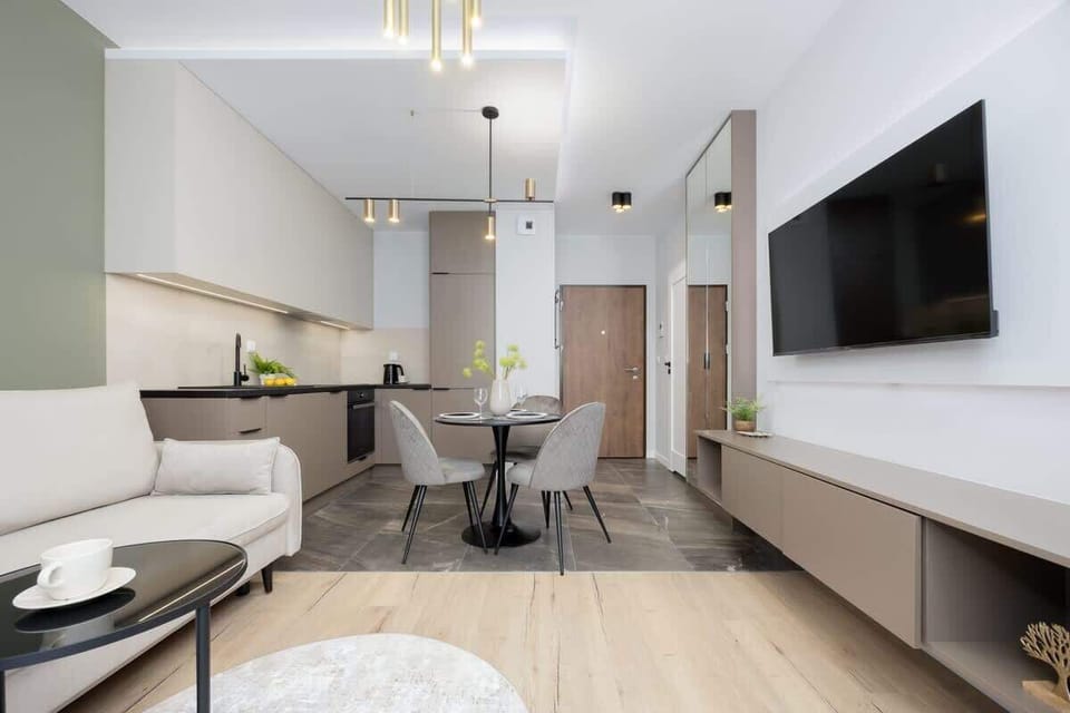 A bright living and dining area with a spacious layout and light wood flooring. The sofa, dining table, and TV zone make it ideal for relaxing or entertaining guests.
