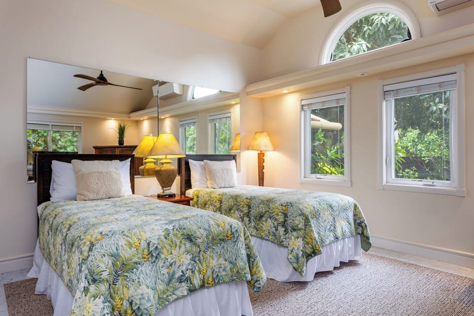 Guest Bedroom - Wake to lush garden views through arched windows in your twin-bedded retreat (can also be configured as a king bed upon request), where tropical-print linens and warm lamplight create your island sanctuary.