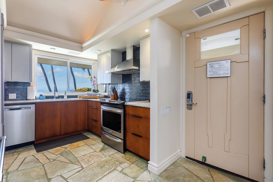 Picture yourself preparing meals in this modern, fully-equipped kitchen with stunning ocean views. Warm wood cabinets, sleek appliances, and a bright coastal backdrop make cooking feel effortless and inspiring.