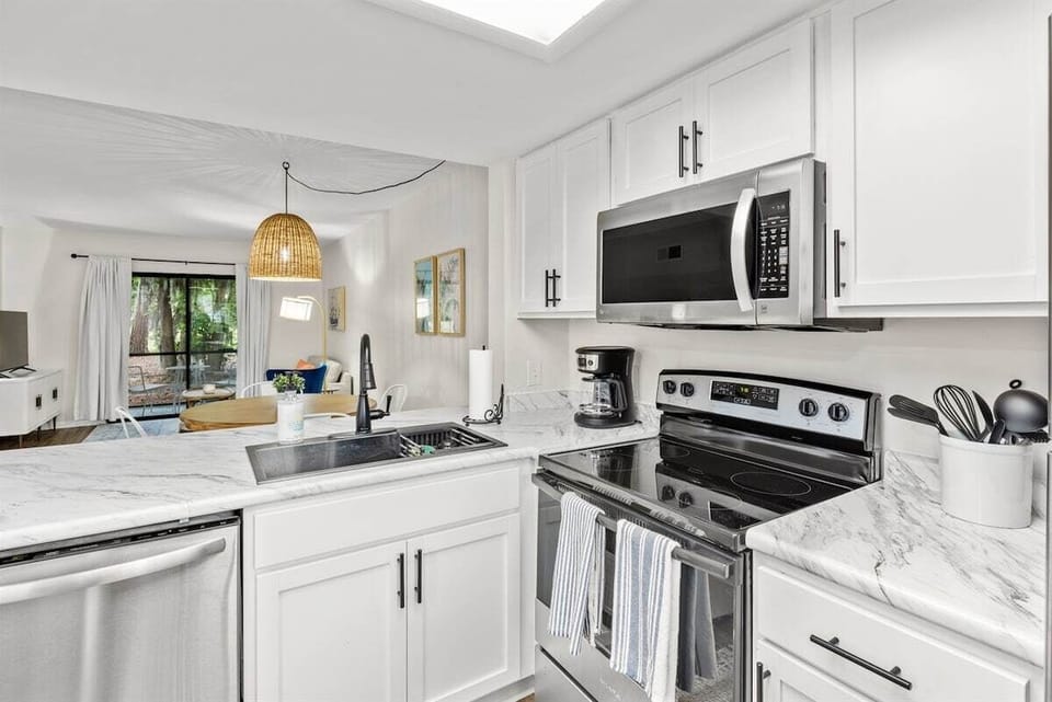 The kitchen is equipped with modern stainless steel appliances, spacious granite countertops, and a central island, perfect for preparing and enjoying meals.