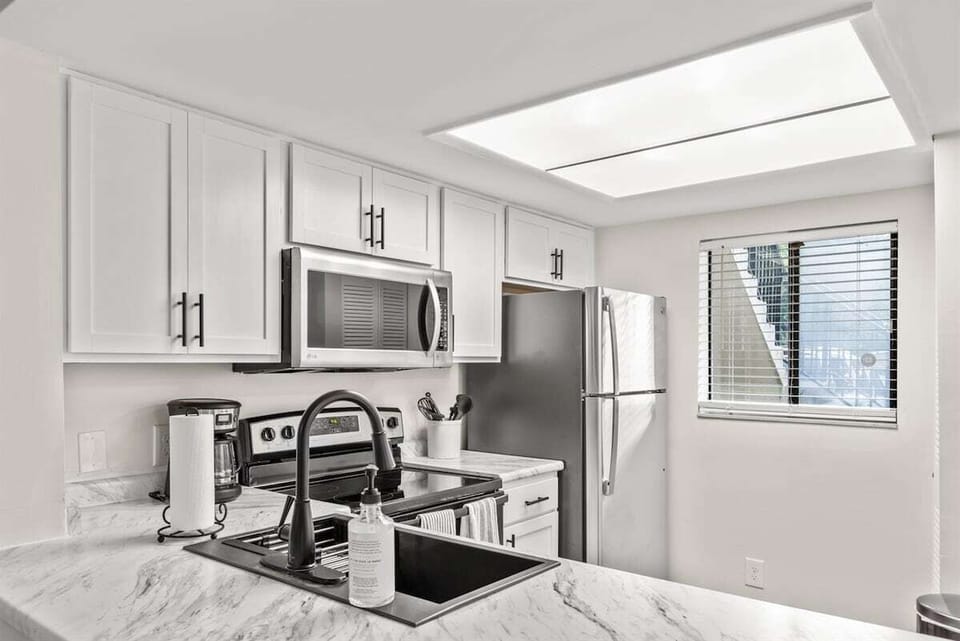 The kitchen is equipped with modern stainless steel appliances, spacious granite countertops, and a central island, perfect for preparing and enjoying meals.