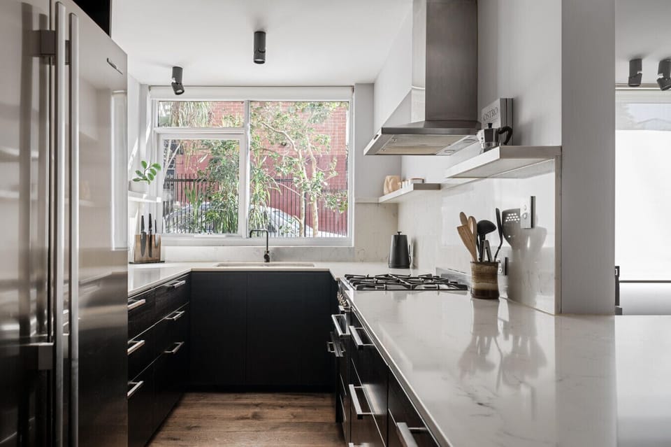 Cook up a storm in this sleek and modern kitchen, complete with stone benchtops, quality appliances, and a sunlit outlook to the garden