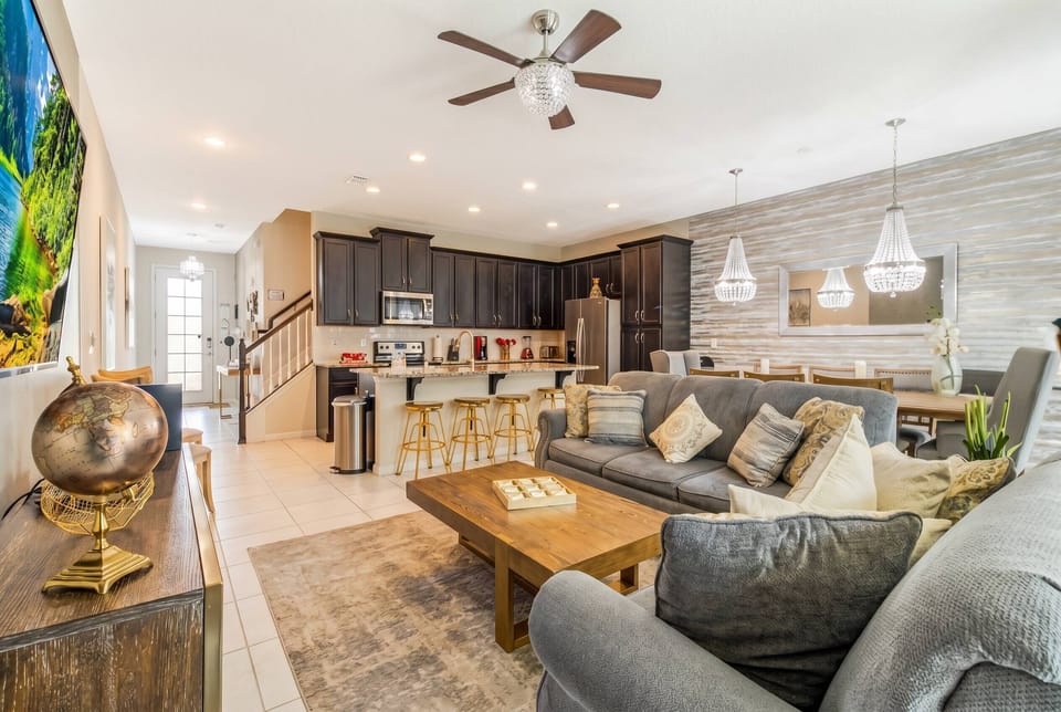 Enjoy a chic living space featuring a plush gray sofa and warm wood coffee table, perfect for unwinding. The elegant pendant lights highlight the rich cabinetry, creating a cozy atmosphere ideal for gatherings with loved ones.