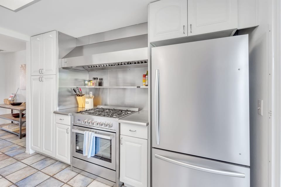 Cook like a pro in a fully-equipped kitchen featuring a Cosmo professional-style gas stove and electric oven, with ample space for multiple cooks to prepare meals together.