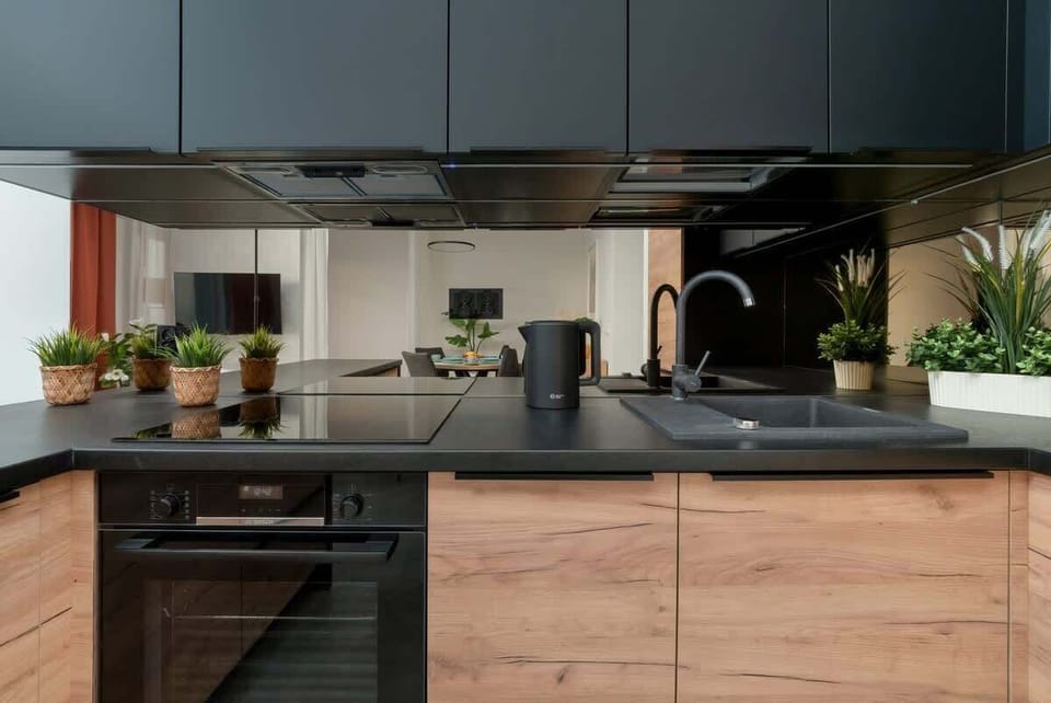 Practical kitchen with black and wooden cabinets and built-in appliances.