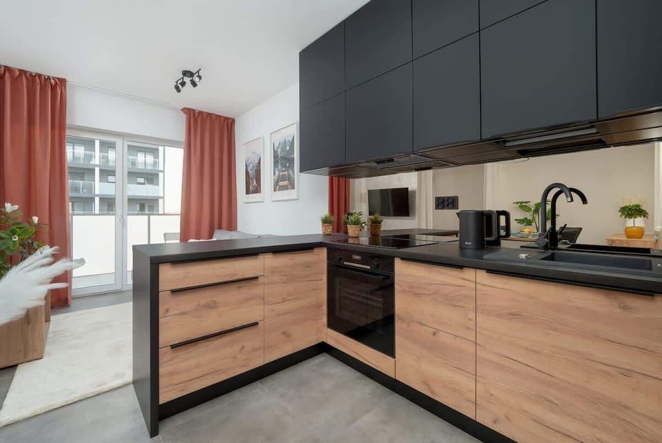 Practical kitchen with black and wooden cabinets and built-in appliances.