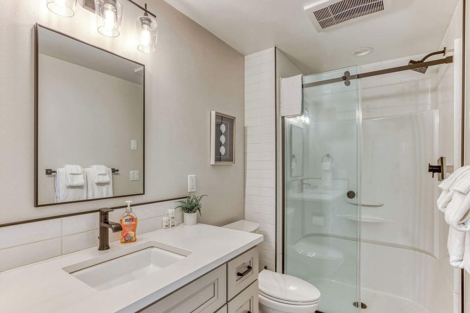 Primary bathroom features a spacious walk-in shower, fresh white towels, and warm-toned decor, creating a cozy yet functional space.