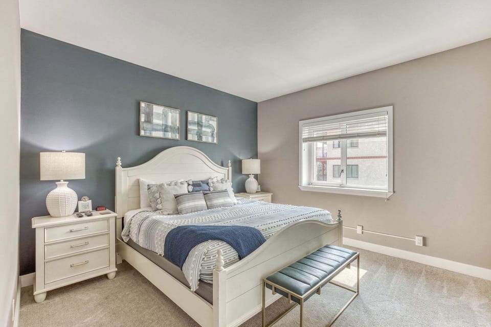 Bright modest primary room featuring a King bed, dedicated bathroom, and a television.