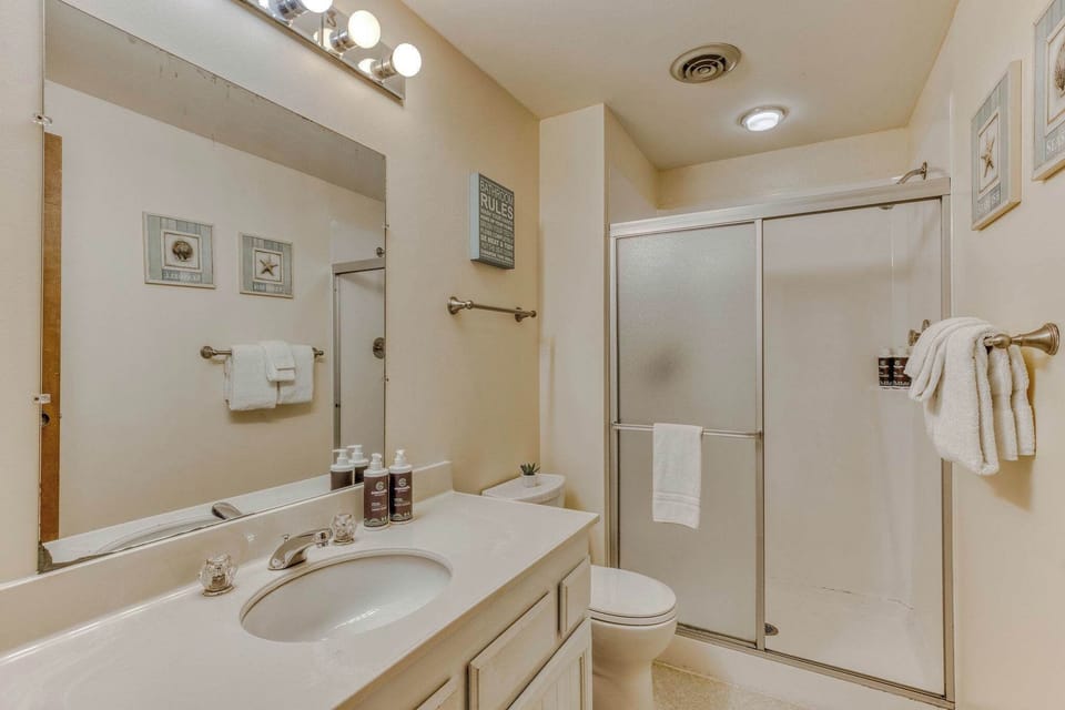 Guest bathroom features a spacious walk-in shower, fresh white towels, and warm-toned decor, creating a cozy yet functional space.