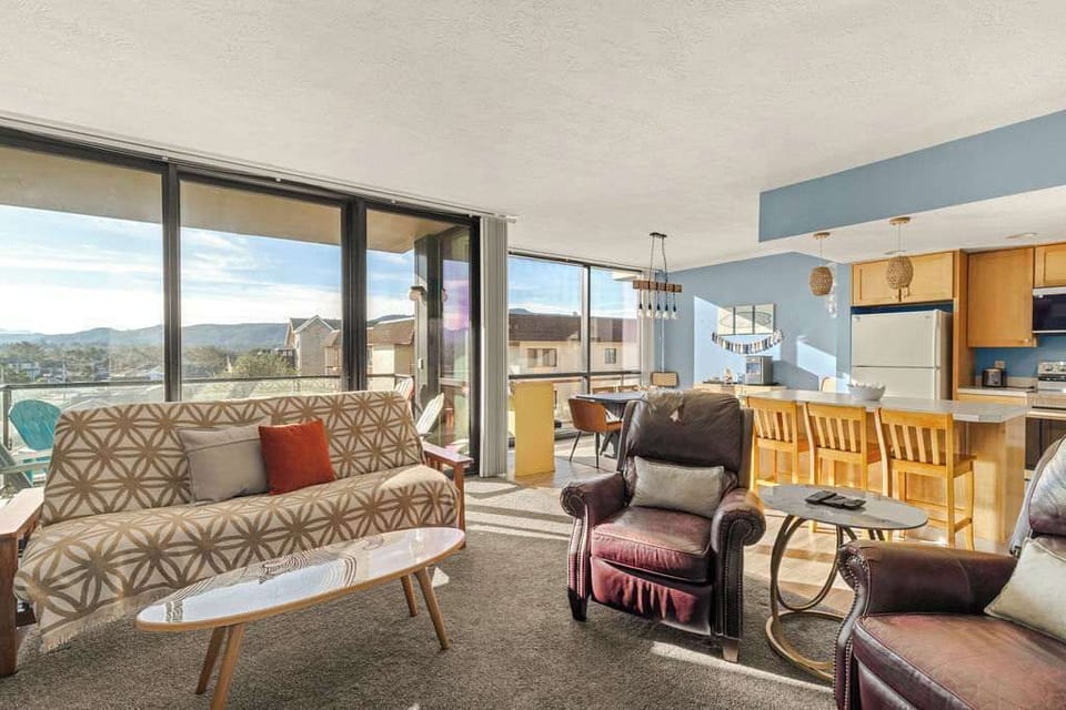 Open-concept living and dining area with large windows, comfortable seating, and plenty of natural light.
