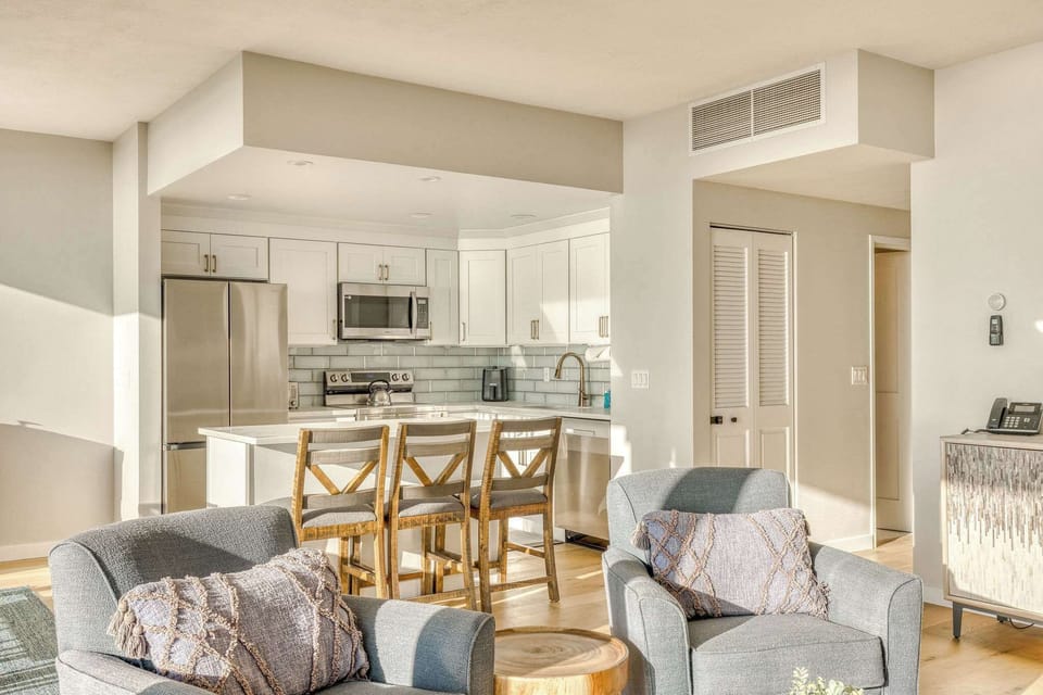 Modern kitchen meets cozy living! This open-concept space features a fully equipped kitchen with island seating and comfortable armchairs for relaxation.