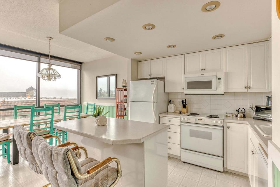 Cook, dine, and socialize with ease! This inviting space boasts a well-appointed kitchen with white cabinetry, a large dining table, and a breakfast bar for flexible seating.