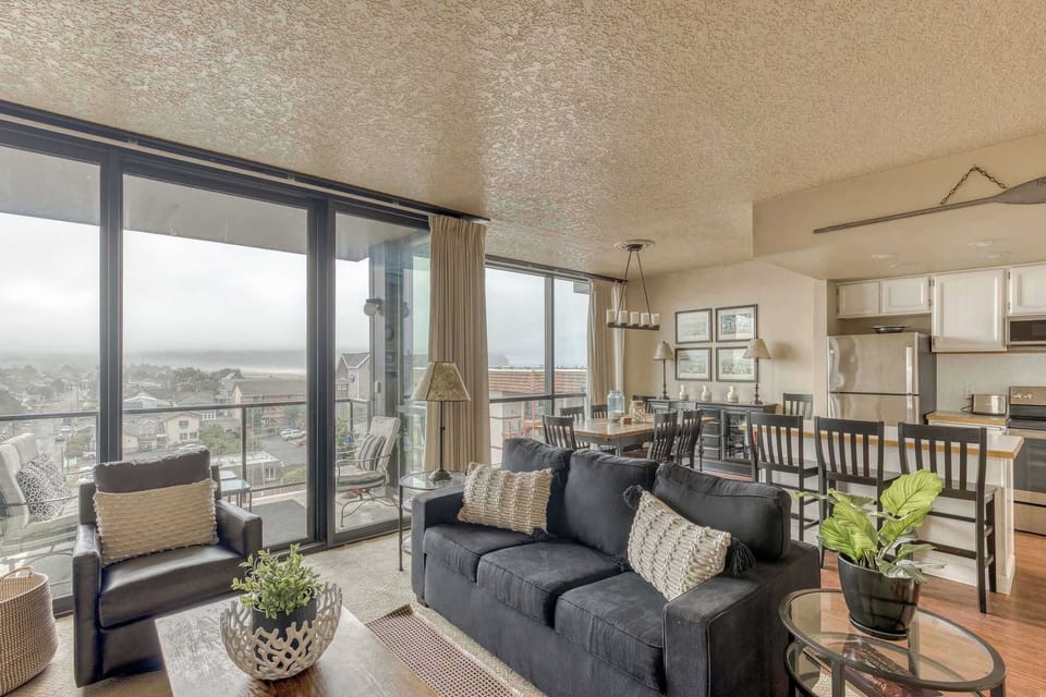 Bright and ready for your vacation enjoyment! This living, dining, and kitchen area offers comfortable furnishings, a vibrant dining table, and stunning window views of the city/coast.