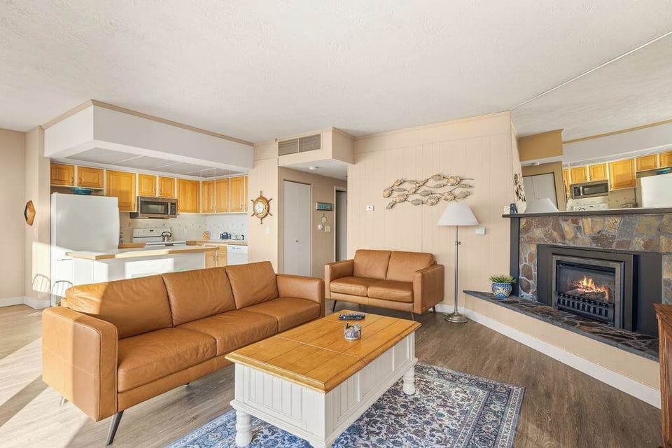 Warm, welcoming living space with fireplace, plush sofas, and an open kitchen for easy gatherings.