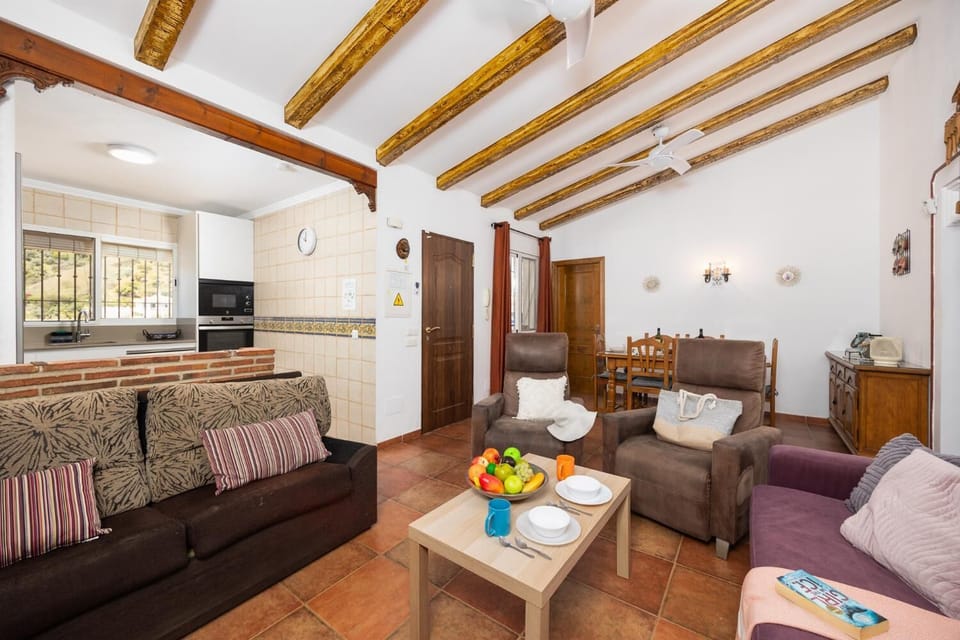 Open-plan living room with sofas, dining area, kitchen, ornamental fireplace, A/C, WiFi internet, and satellite TV