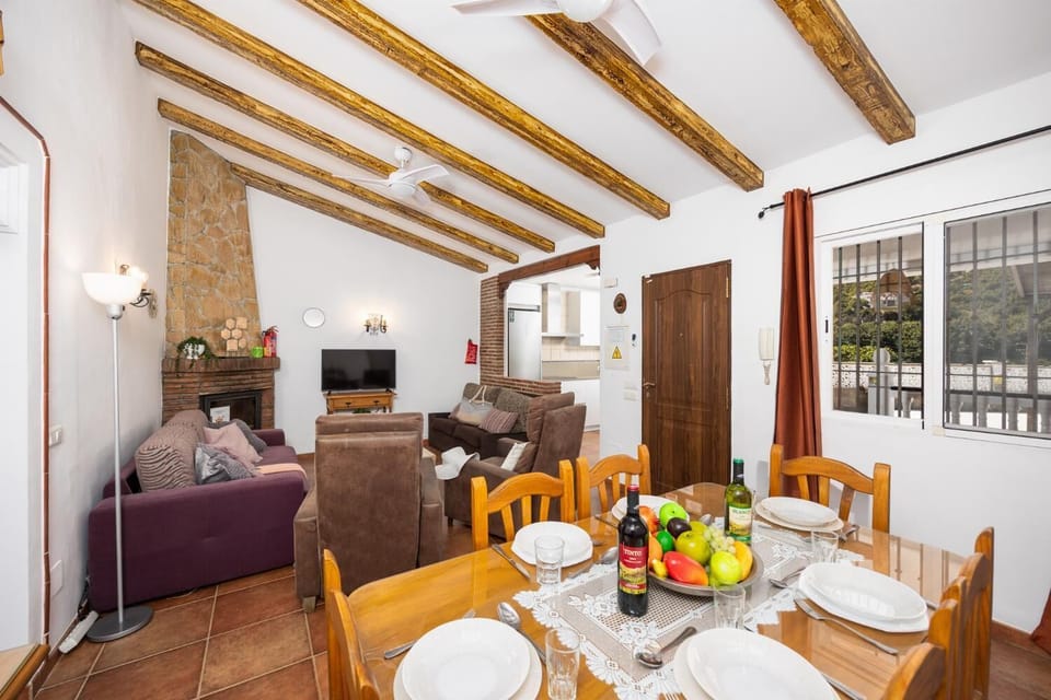 Open-plan living room with sofas, dining area, kitchen, ornamental fireplace, A/C, WiFi internet, and satellite TV