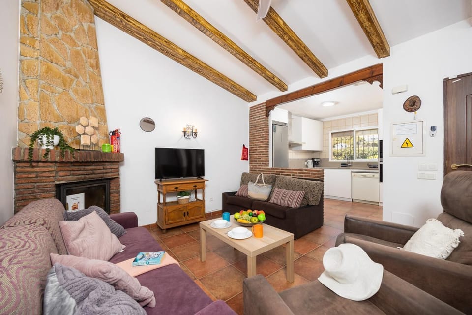 Open-plan living room with sofas, dining area, kitchen, ornamental fireplace, A/C, WiFi internet, and satellite TV