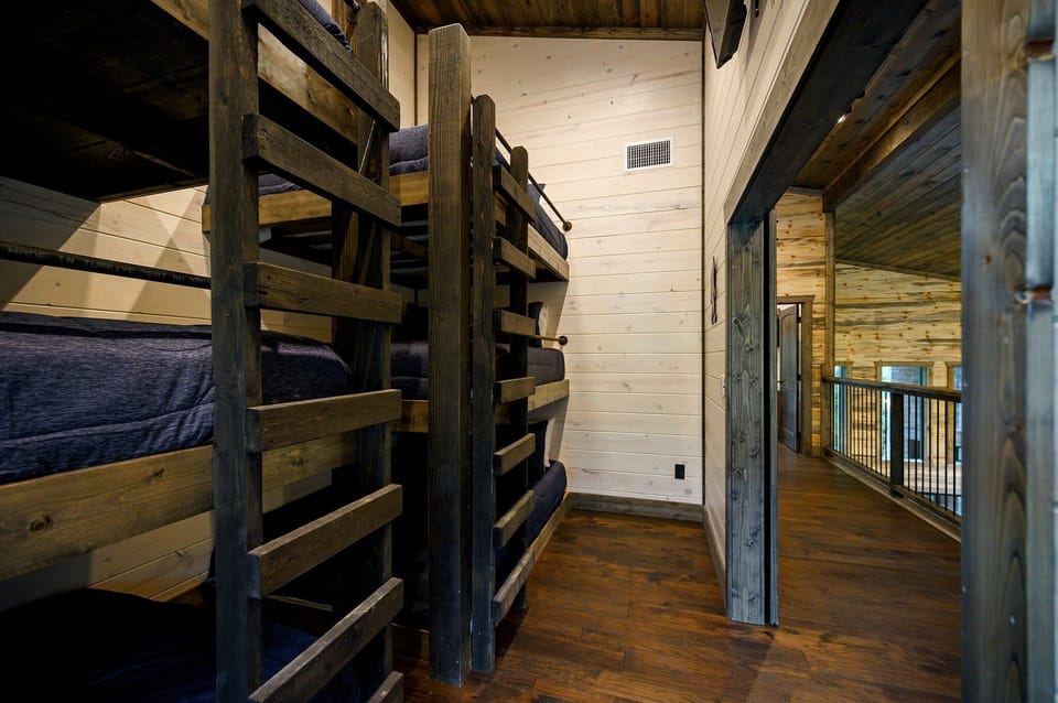 Bunk room w/ 3 queen beds, 3 full beds and smart tv, located upstairs.