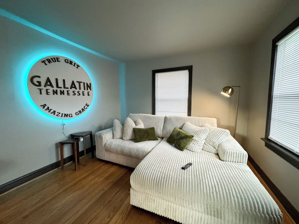 Comfy White Couch / Neon Gallatin Sign / Hardwoods and lots of natural light